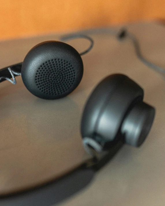 a pair of headphones sitting on top of a table, close - up of the faces, black matte finish, thumbnail, 2070