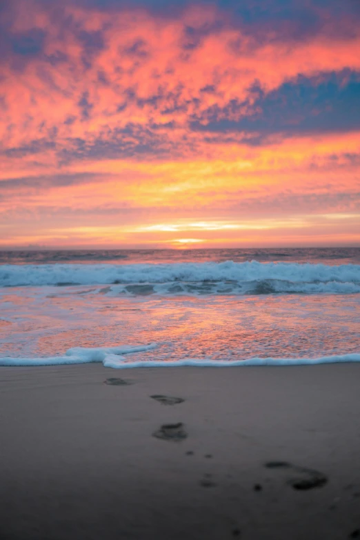 a sunset at the beach with footprints in the sand, by Kristin Nelson, happening, 4k serene, avalon, a colorful, dan