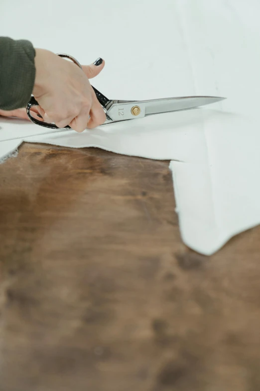 a person cutting a piece of paper with a pair of scissors, oiled hardwood floors, white soft leather model, folds of fabric, 64x64