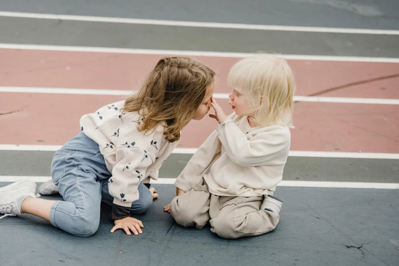 a couple of little girls sitting on top of a tennis court, by Emma Andijewska, pexels contest winner, peasant boy and girl first kiss, looking at each other mindlessly, toddler, sitting on the ground