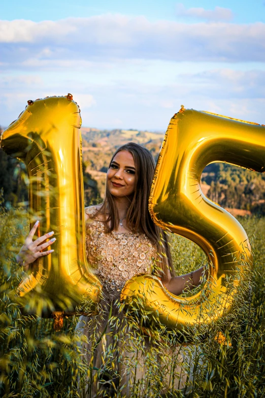 a woman standing in a field holding a golden number 25 balloon, 1614572159, glam photo, nice view, 1 6 years old