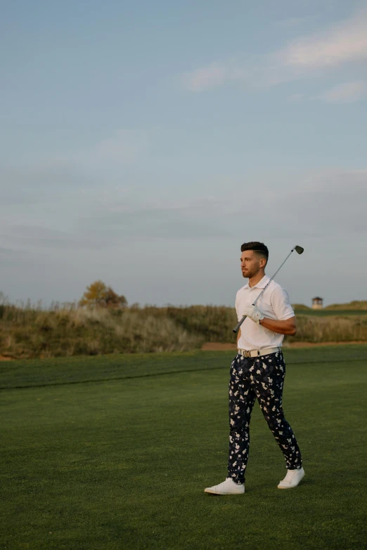 a man standing on top of a green field holding a golf club, by Robbie Trevino, patterned clothing, zayn malik, profile image, wearing only pants