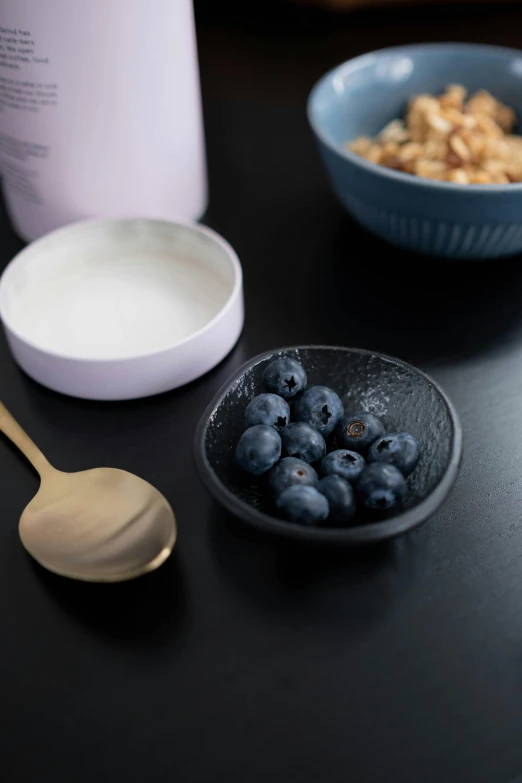 a table topped with a bowl of blueberries and a bowl of yogurt, inspired by Peter de Sève, trending on unsplash, dark matte metal, with small object details, subtle purple accents, detail shot