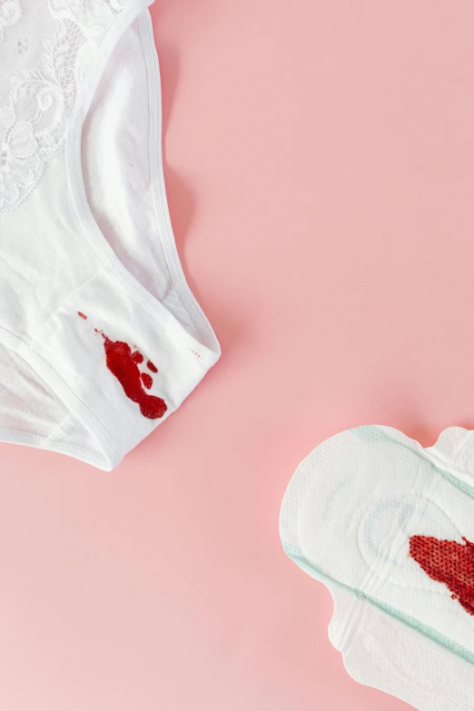 a pair of underwear sitting on top of a pink surface, blood on body, detailed product image, white, diaper-shaped