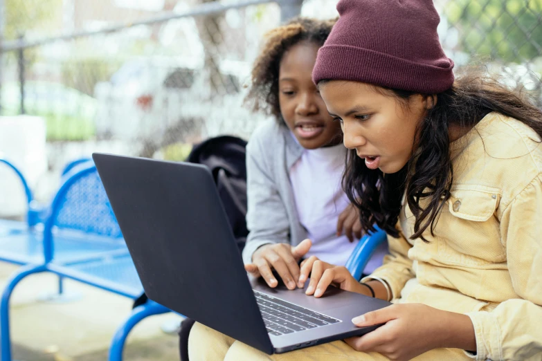 a woman sitting on a bench using a laptop computer, by Carey Morris, trending on pexels, two girls, square, raging, school