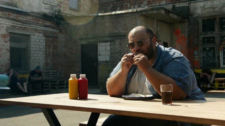 a man sitting at a table with a plate of food, lucas films, fat belly, in an urban setting, hasbulla magomedov