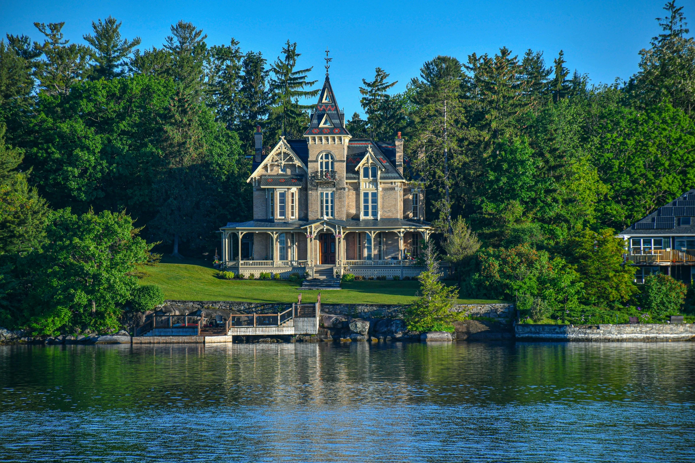 a large house sitting on top of a lush green hillside, on a lake, stunning grand architecture, slide show, victorian setting