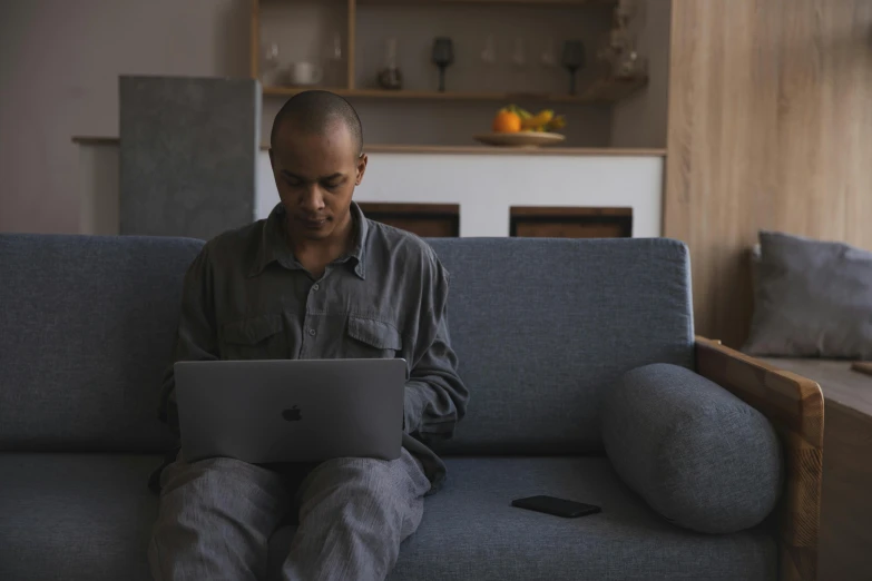 a man sitting on a couch using a laptop, inspired by Afewerk Tekle, pexels contest winner, ( ( theatrical ) ), brown, engineer, hunting