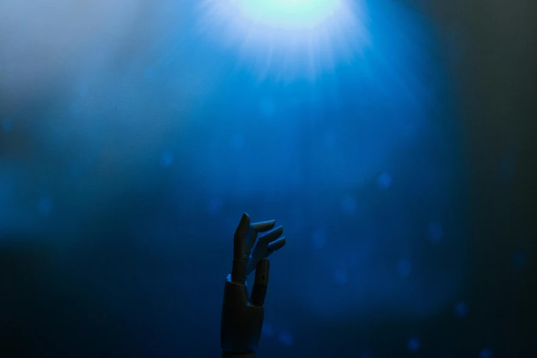 a person holding their hand up in the air, light and space, dramatic blue light, looking upward, lights off, promo image