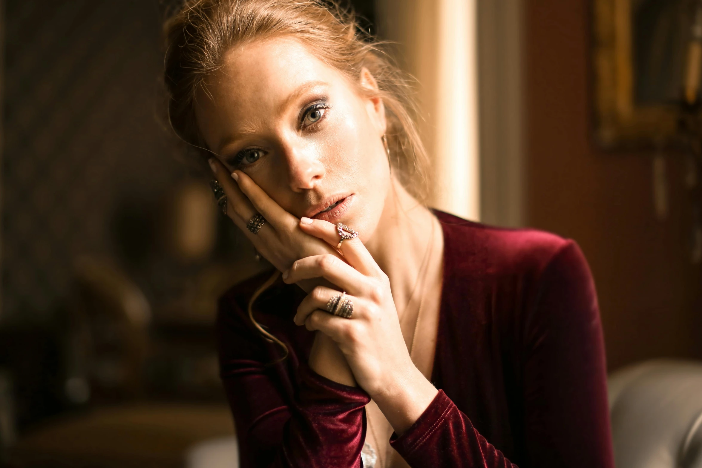 a woman sitting on a couch with her hand on her chin, a portrait, by Emma Andijewska, trending on pexels, renaissance, wearing two metallic rings, jessica chastain, britt marling style, dressed in velvet