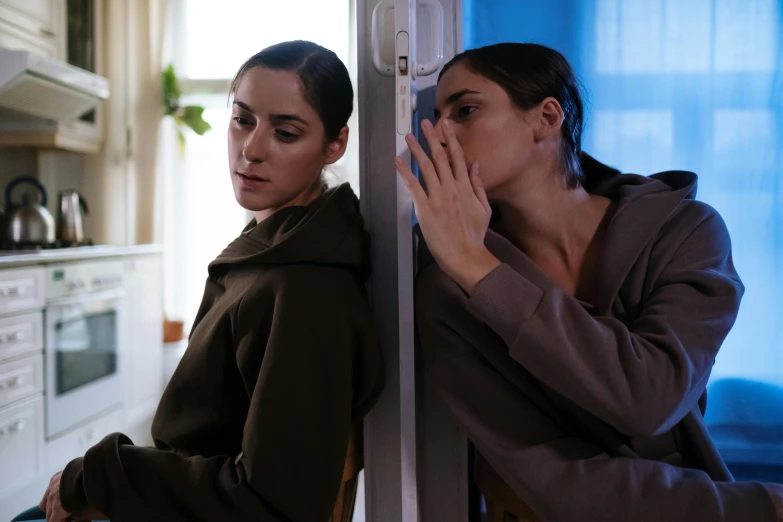 a couple of women standing next to each other, by Elsa Bleda, trending on pexels, serial art, tv still frame, leaning on door, concerned, girl wearing hoodie