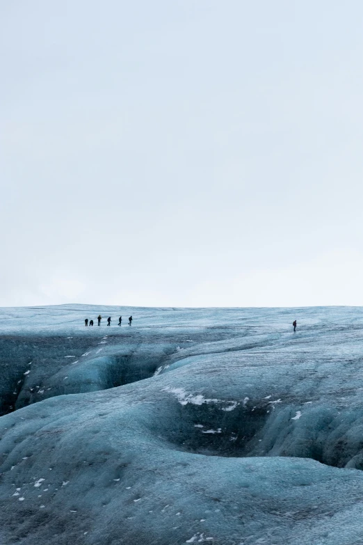 a group of people standing on top of a glacier, by Jesper Knudsen, unsplash contest winner, minimalism, ice blue, walking to the right, 8 k ), from afar