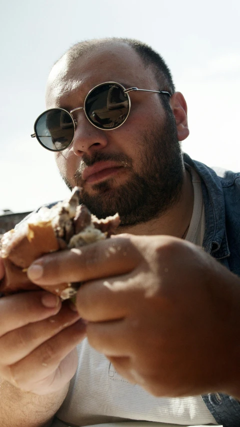 a man sitting at a table eating a sandwich, an album cover, by Matt Cavotta, unsplash, obese ), low quality photo, outdoor photo, shades