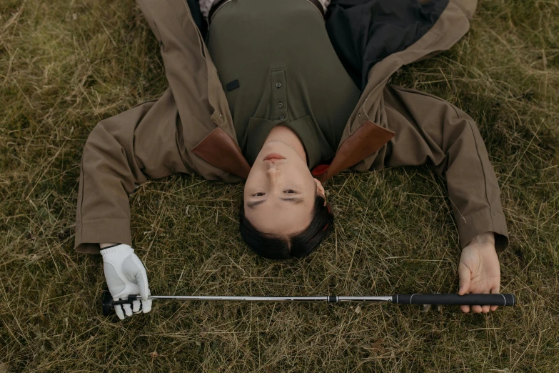 a man laying in the grass with a golf club, inspired by Marina Abramović, unsplash, realistic cosplay, arya stark, ignant, the falling soldier