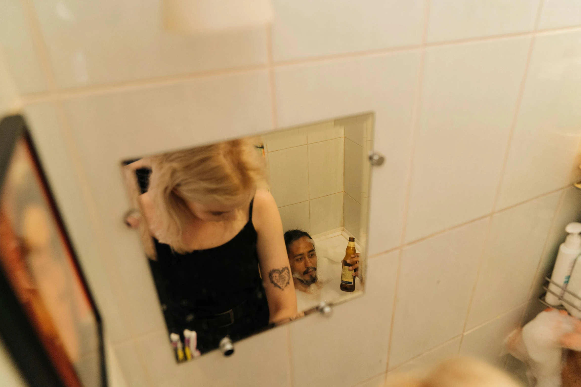 a woman standing in front of a mirror in a bathroom, a photo, inspired by Nan Goldin, happening, blonde man, with tiny people, top - down photograph, hiding