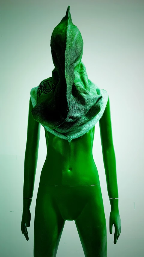 a woman in a green bodysuit with a hood over her head, a surrealist sculpture, inspired by Anna Füssli, showstudio, on a mannequin. high resolution, body made of glass, muslim