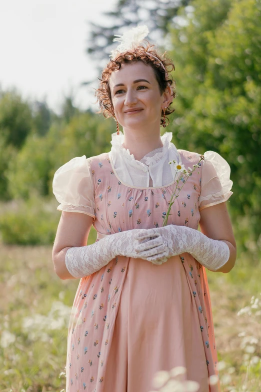 a woman in a pink dress standing in a field, a portrait, inspired by Cassandra Austen, shutterstock, still image from tv series, wearing gloves, slight friendly smile, ( ( theatrical ) )