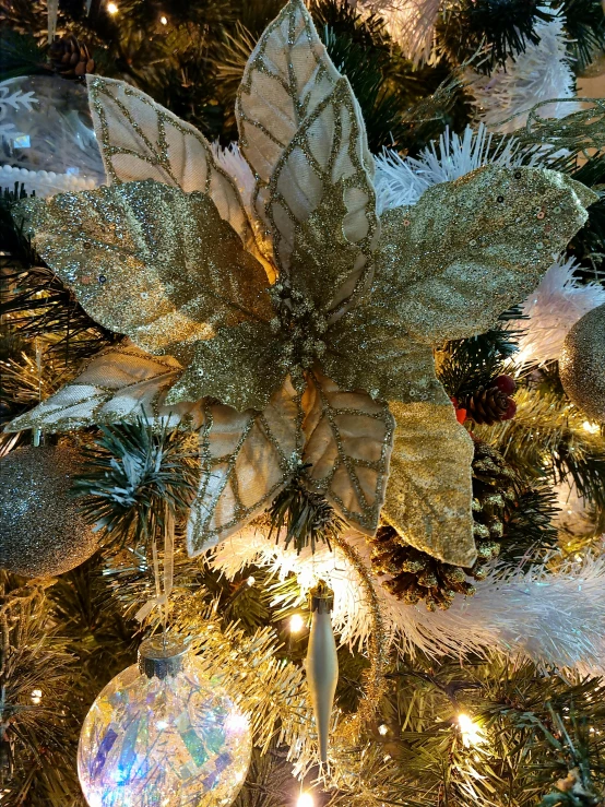 a close up of a christmas tree with ornaments, gold flowers, silver with gold trim, zoomed in shots, caparisons