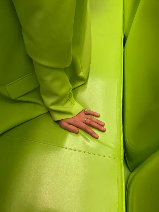 a person standing on top of a green couch, inspired by Ren Hang, trending on unsplash, subject detail: wearing a suit, fluorescent skin, extreme hand detail, photographed for reuters