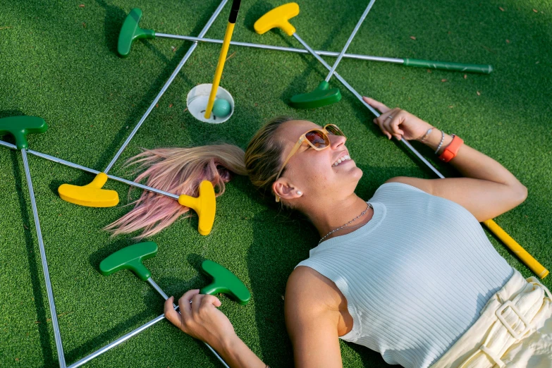 a woman laying on the ground playing golf, by Julia Pishtar, turf roof, headspace, everyone having fun, top down