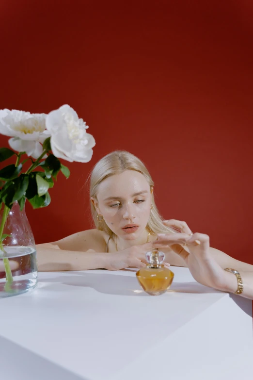 a woman sitting at a table with a glass of orange juice, floating in perfume, lily frank, kirsi salonen, holding daisy