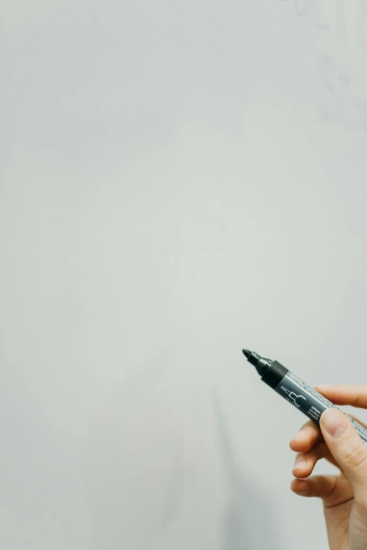 a person writing on a white board with a pen, by Carey Morris, pexels contest winner, solid light grey background, black paint, gray color, gradient black to silver