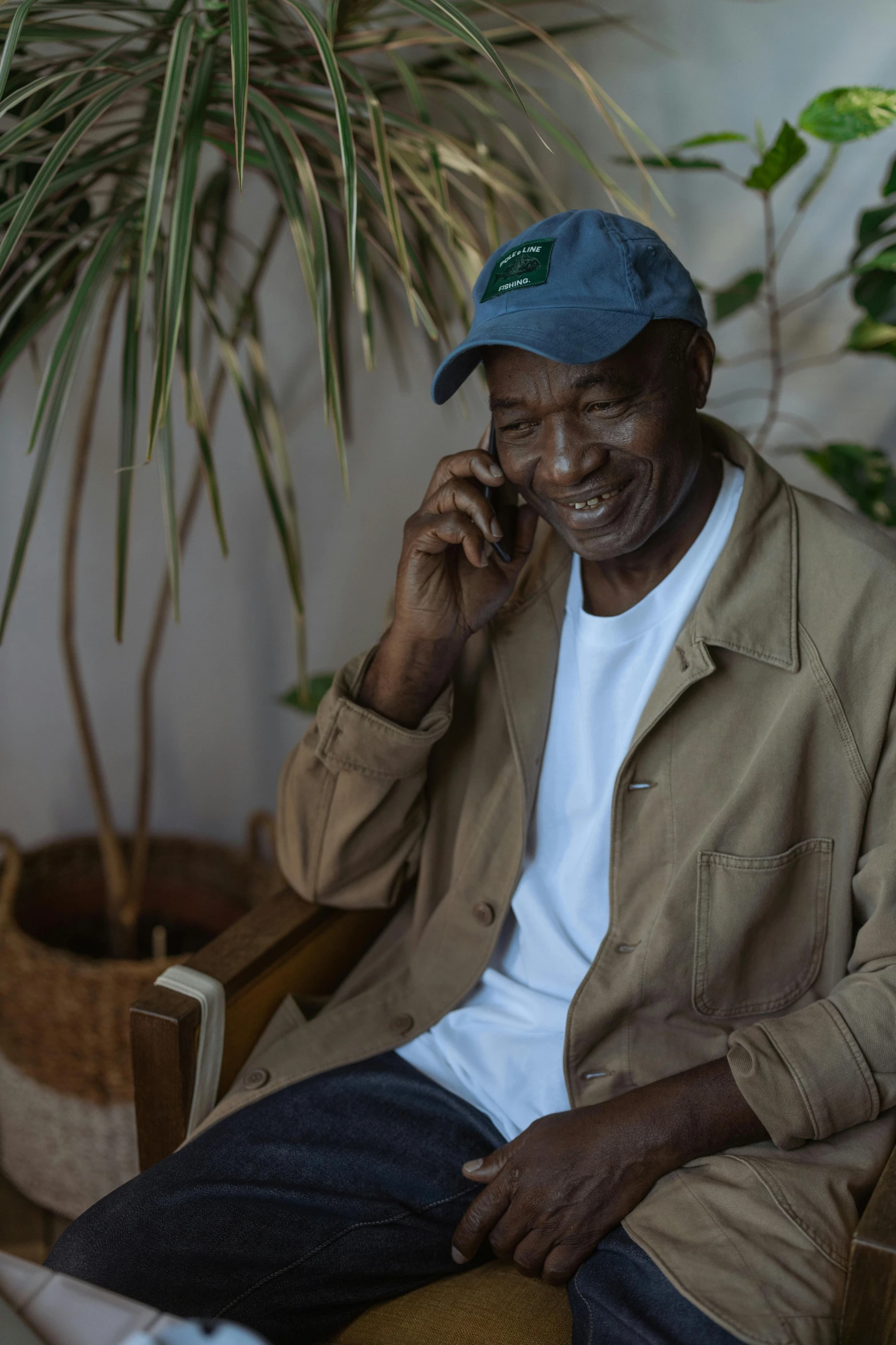 a man sitting in a chair talking on a cell phone, mongezi ncaphayi, grandfatherly, in a dark green polo shirt, ignant