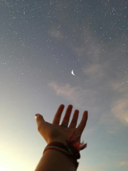 a person reaching up to the sky with the moon in the background, an album cover, trending on unsplash, hurufiyya, ☁🌪🌙👩🏾, hand instead of a face, stargazer, low quality photo