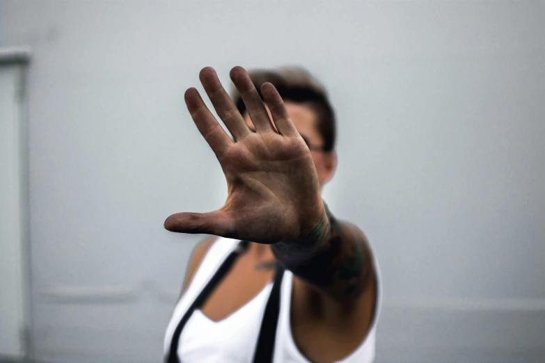 a woman holding her hand up in the air, a tattoo, unsplash, bauhaus, portrait image, zyzz, 5 5 mm photo, blank stare