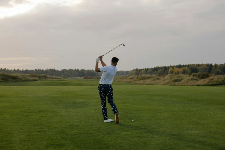 a man standing on top of a green field holding a golf club, a picture, inspired by Sven Nordqvist, unsplash, patterned clothing, mid action swing, mid night, knees upturned