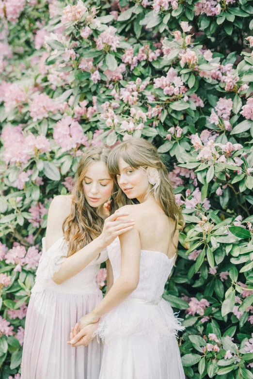 two women standing next to each other in front of flowers, inspired by Oleg Oprisco, trending on pexels, wedding, 🎀 🧟 🍓 🧚, brunettes, 15081959 21121991 01012000 4k