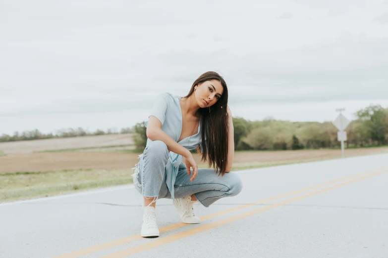 a woman squatting down on the side of the road, trending on pexels, realism, :: madison beer, pale blue outfit, joanna gaines, androgynous person