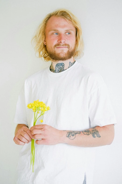 a man holding a bunch of yellow flowers, inspired by Lasar Segall, featured on reddit, aestheticism, plain white tshirt, small blond goatee, studio portrait, lil peep