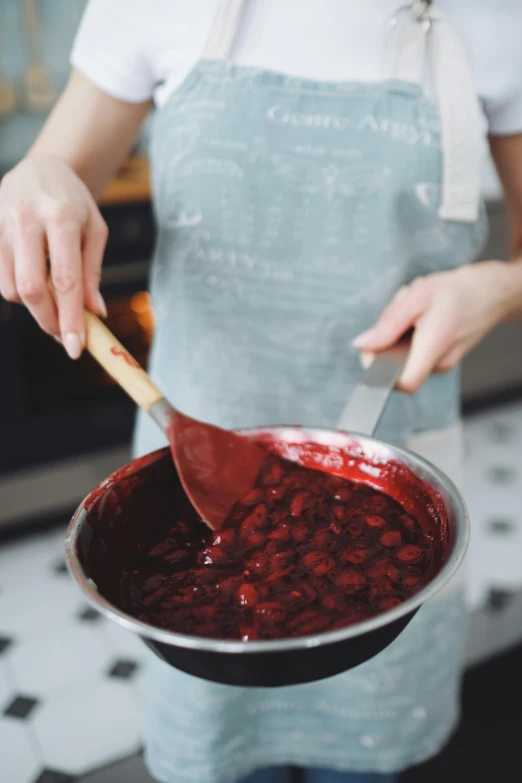 a close up of a person holding a pan of food, cherries, in a kitchen