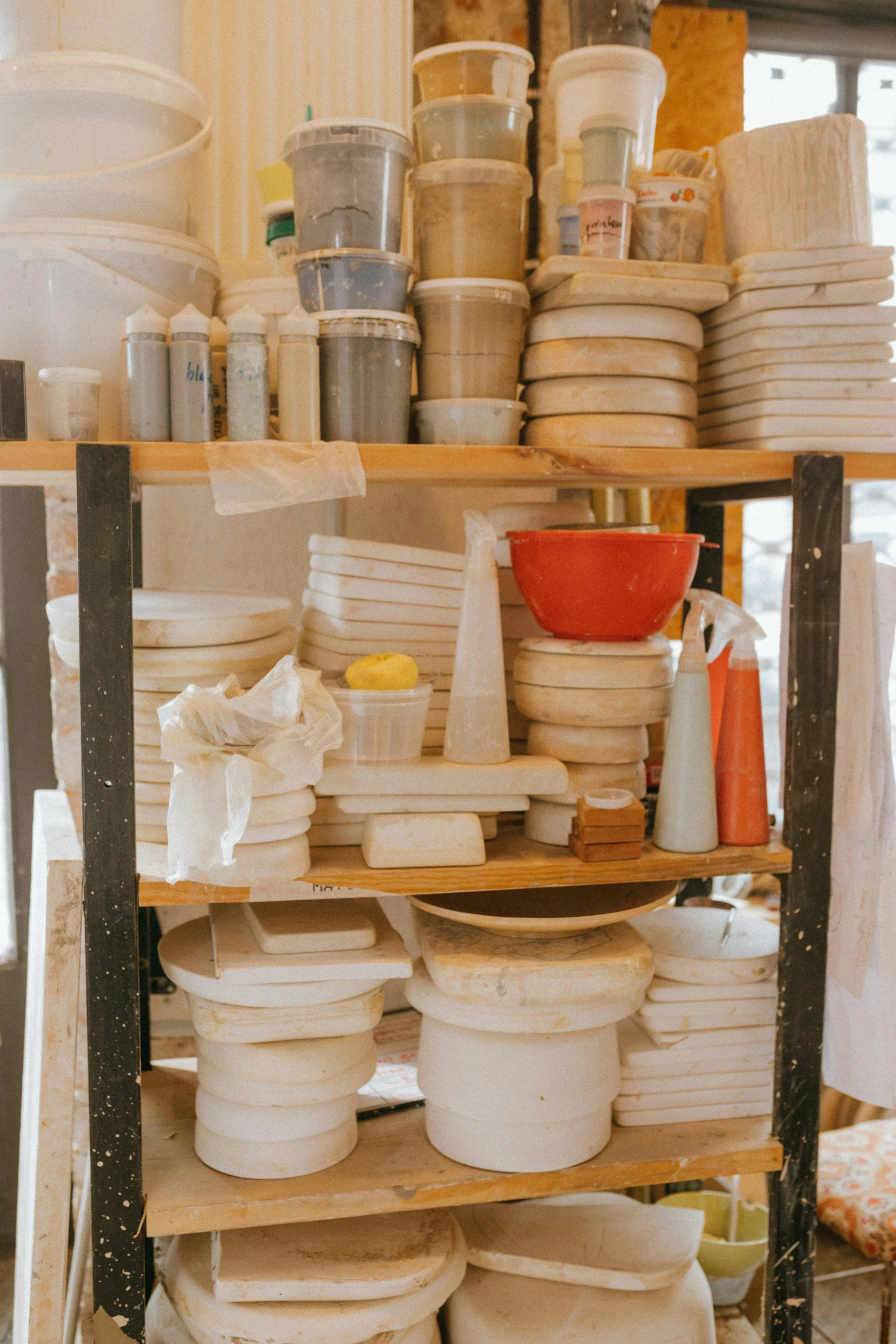 a room filled with lots of plates and bowls, studio lights, rack, material, shelf