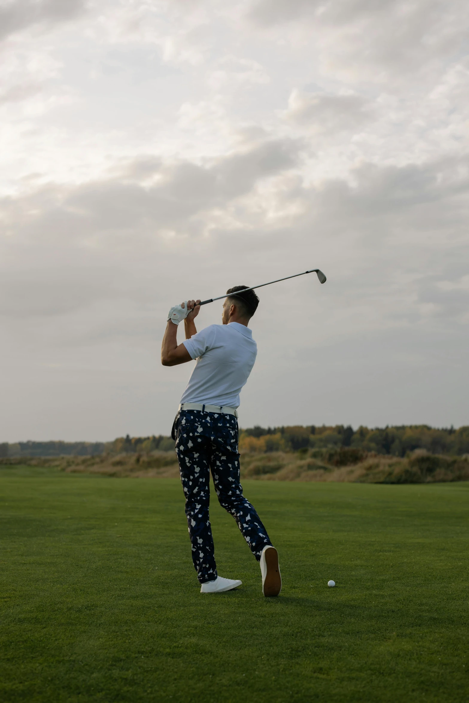 a man swinging a golf club on a cloudy day, a picture, unsplash, patterned clothing, late summer evening, gif, low iso
