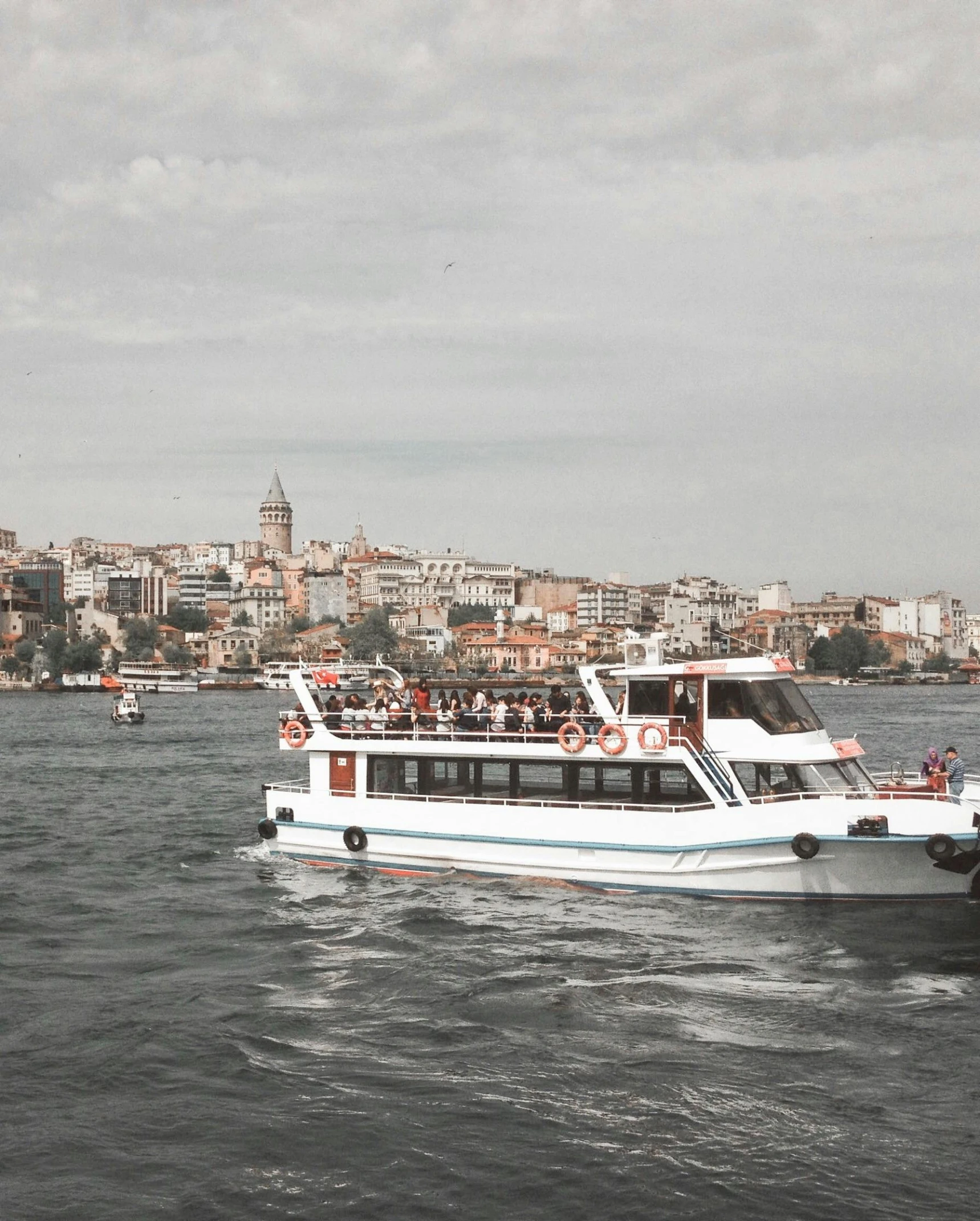 a boat on a body of water with a city in the background, full of people, thumbnail, istanbul, lgbtq