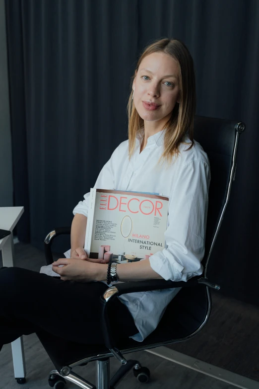 a woman sitting in a chair holding a book, kirsi salonen, fashion designer, profile image, professional profile photo