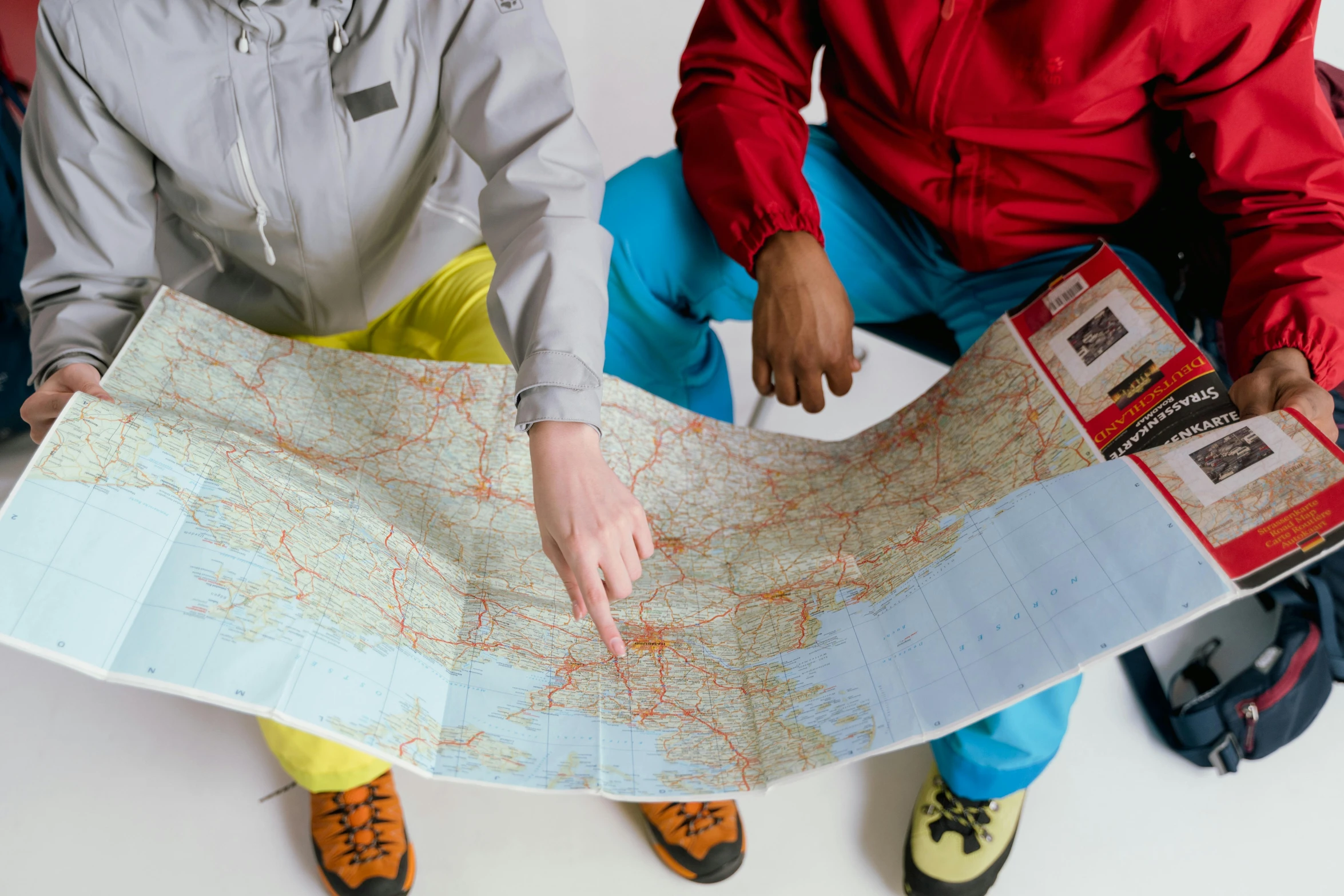 a couple of people that are looking at a map, regionalism, wearing adventure gear, gray, diverse, multi-part