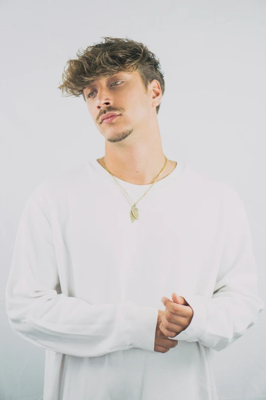 a man standing in front of a white wall, an album cover, inspired by Luca Zontini, trending on pexels, renaissance, wearing white v - neck top, headshot profile picture, gold chains, caspar david