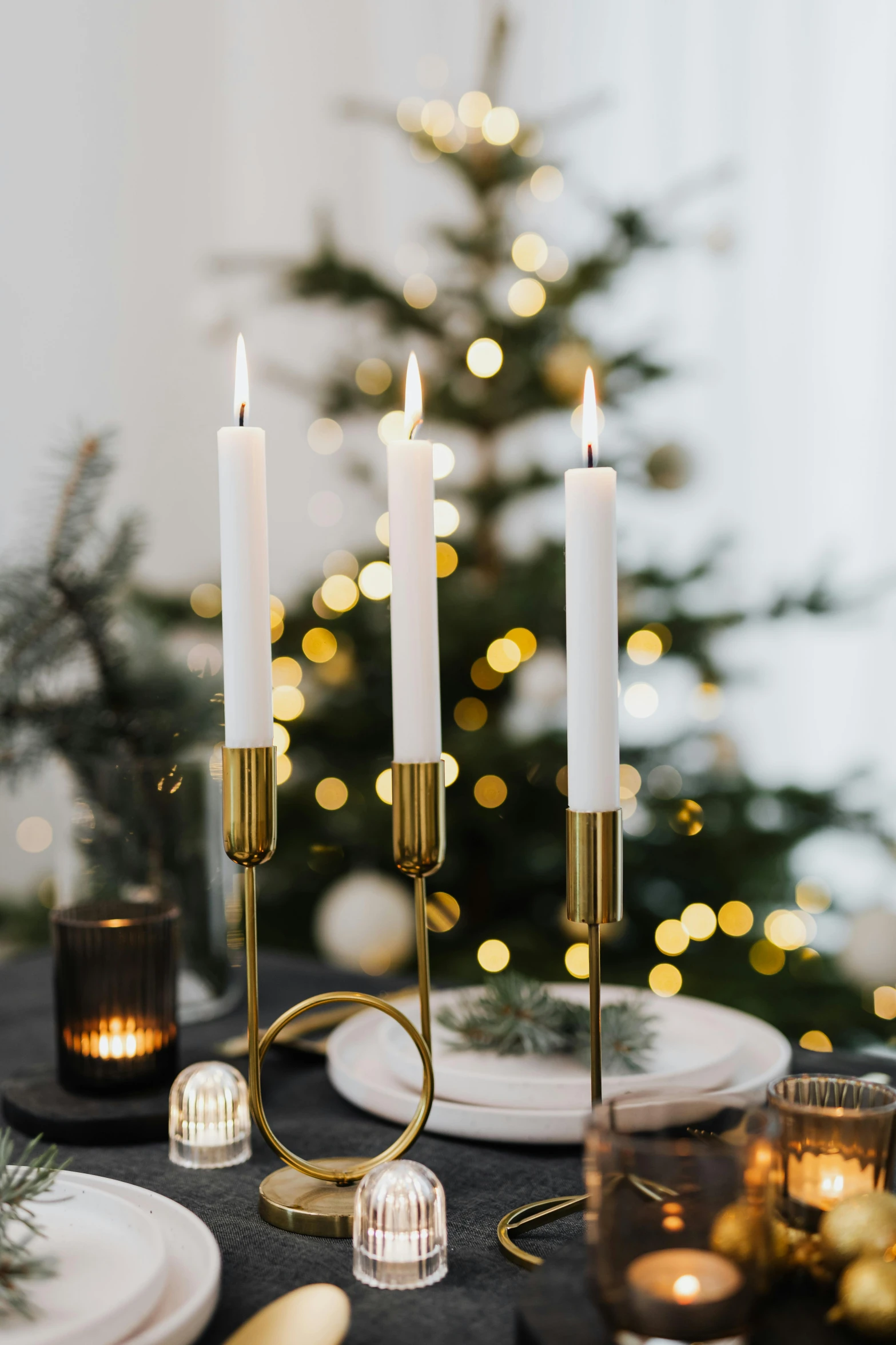 a black table topped with candles next to a christmas tree, by Julia Pishtar, gold plated, beautifully bright white, natural candle lighting, beautifully soft lit