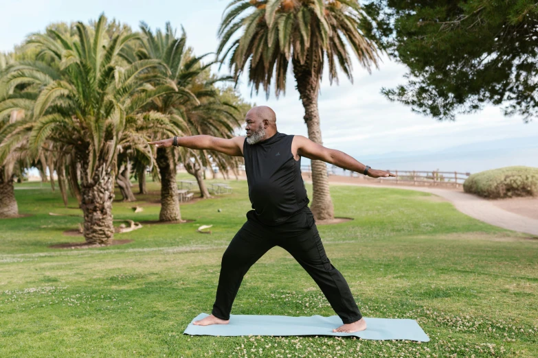 a man standing on a yoga mat in a park, by Carey Morris, pexels contest winner, samuel l jackson, synthetic curves striking pose, mediterranean, avatar image