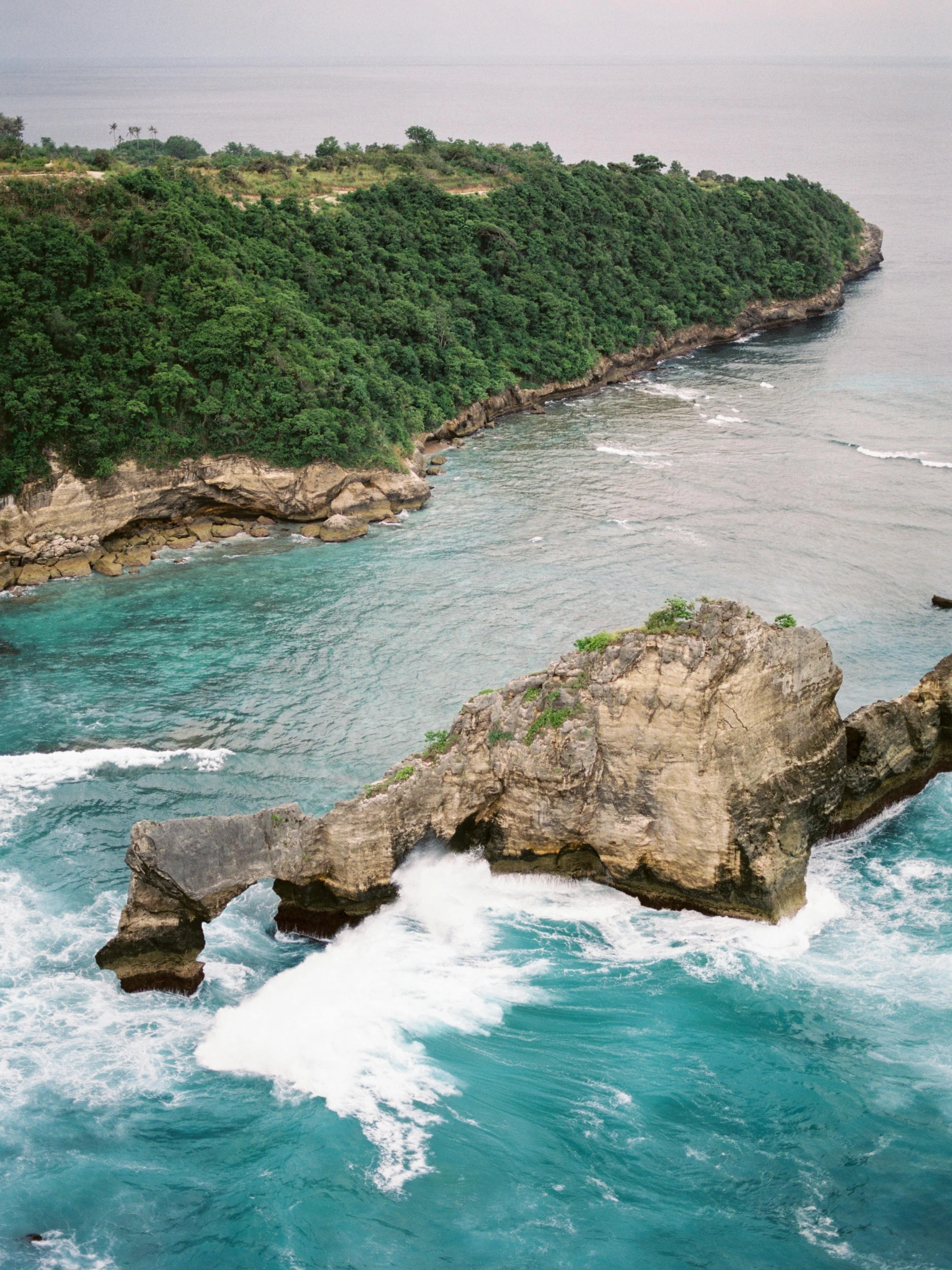 a small island in the middle of the ocean, by Jessie Algie, pexels contest winner, sumatraism, rock arches, high angle close up shot, rough waves, panoramic