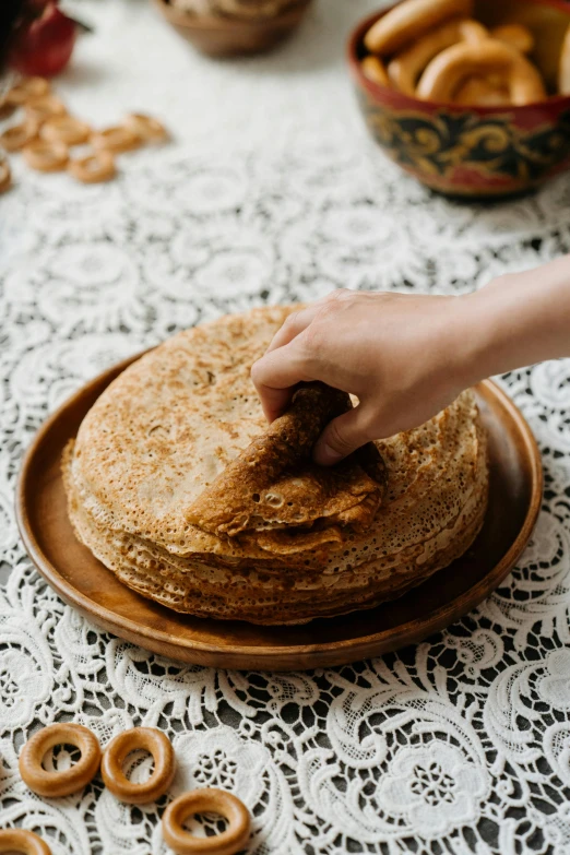 a person reaching for a stack of pancakes, an album cover, by Julia Pishtar, trending on unsplash, folk art, traditional russia, fine lace, 15081959 21121991 01012000 4k, bread