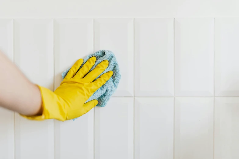 a person in yellow gloves cleaning a white tiled wall, by Nicolette Macnamara, fan favorite, perfectly tileable, without text, profile image