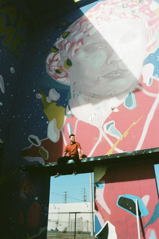 a large painting on the side of a building, a picture, inspired by James Jean, pexels contest winner, process art, shot on superia 400 filmstock, sitting down casually, flume, guy