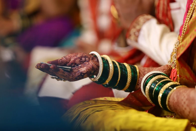 a close up of a person holding a cell phone, blue colored traditional wear, bangles, ornate attire, profile image