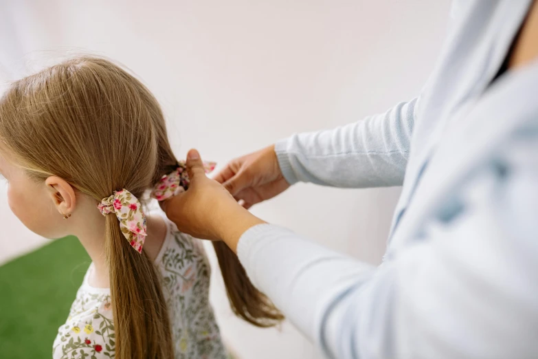 a little girl getting her hair done by a woman, pexels contest winner, hurufiyya, ornamental bow, press shot, loosely cropped, half image