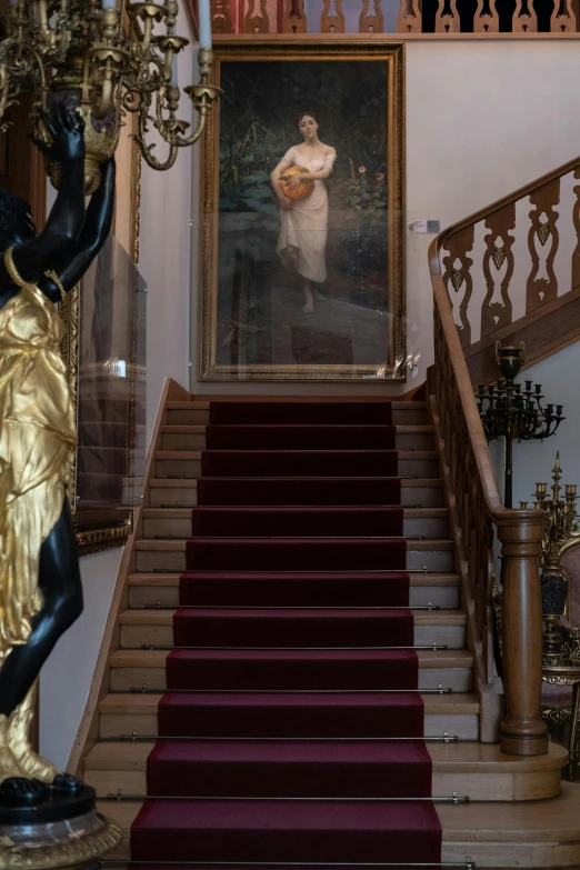 a staircase in a building with a painting on the wall, a statue, inspired by Anders Zorn, baroque, gold and red accents, very very aesthetic, doing an elegant pose over you, inside a grand studio