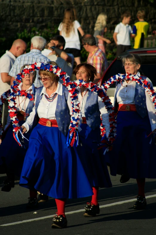 a group of people that are walking down the street, red and blue garments, as though she is dancing, americana, ribbon